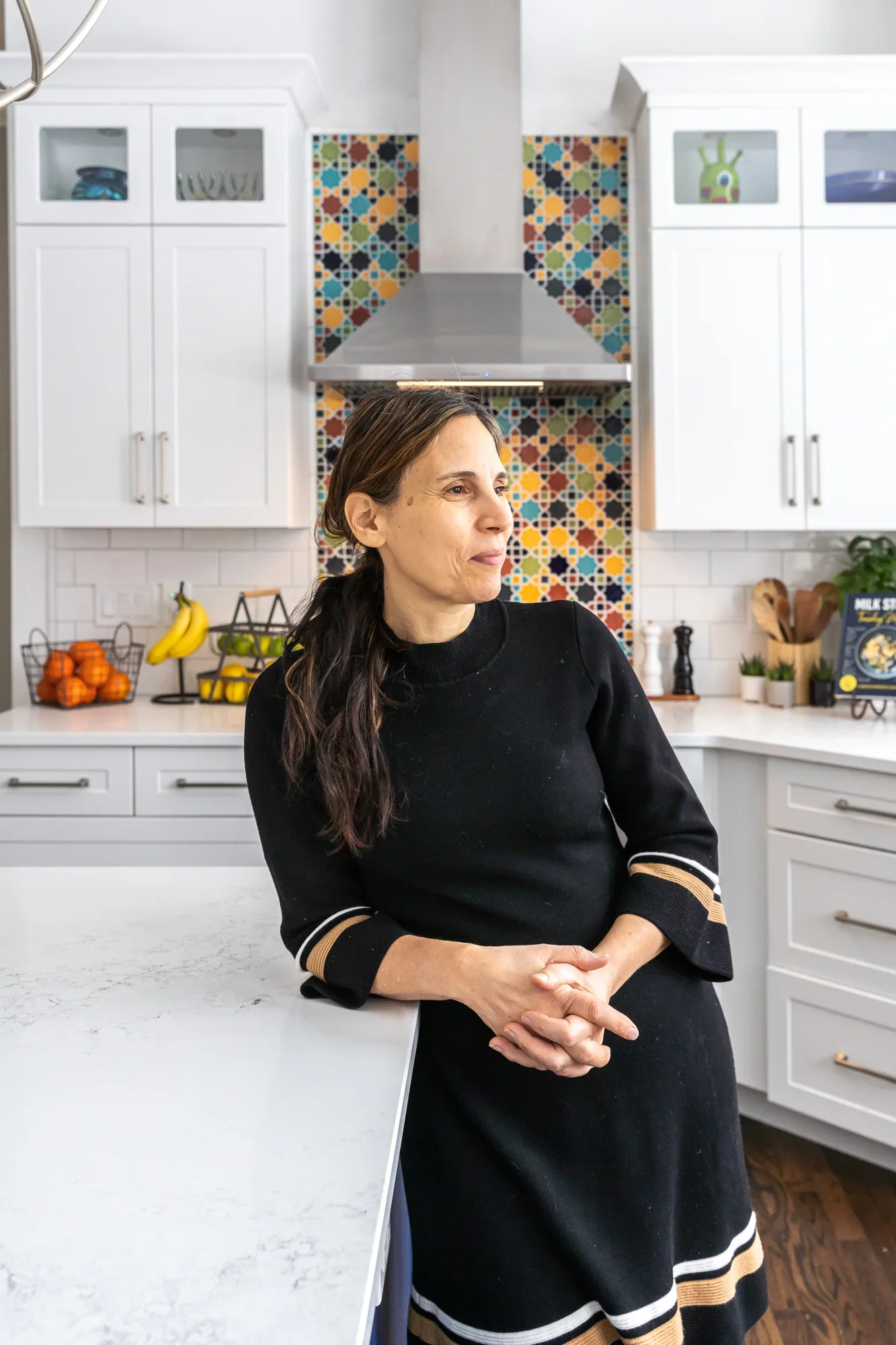 White kitchen cabinets, Moroccan tile backsplash, stainless steel range hood, quartz counters