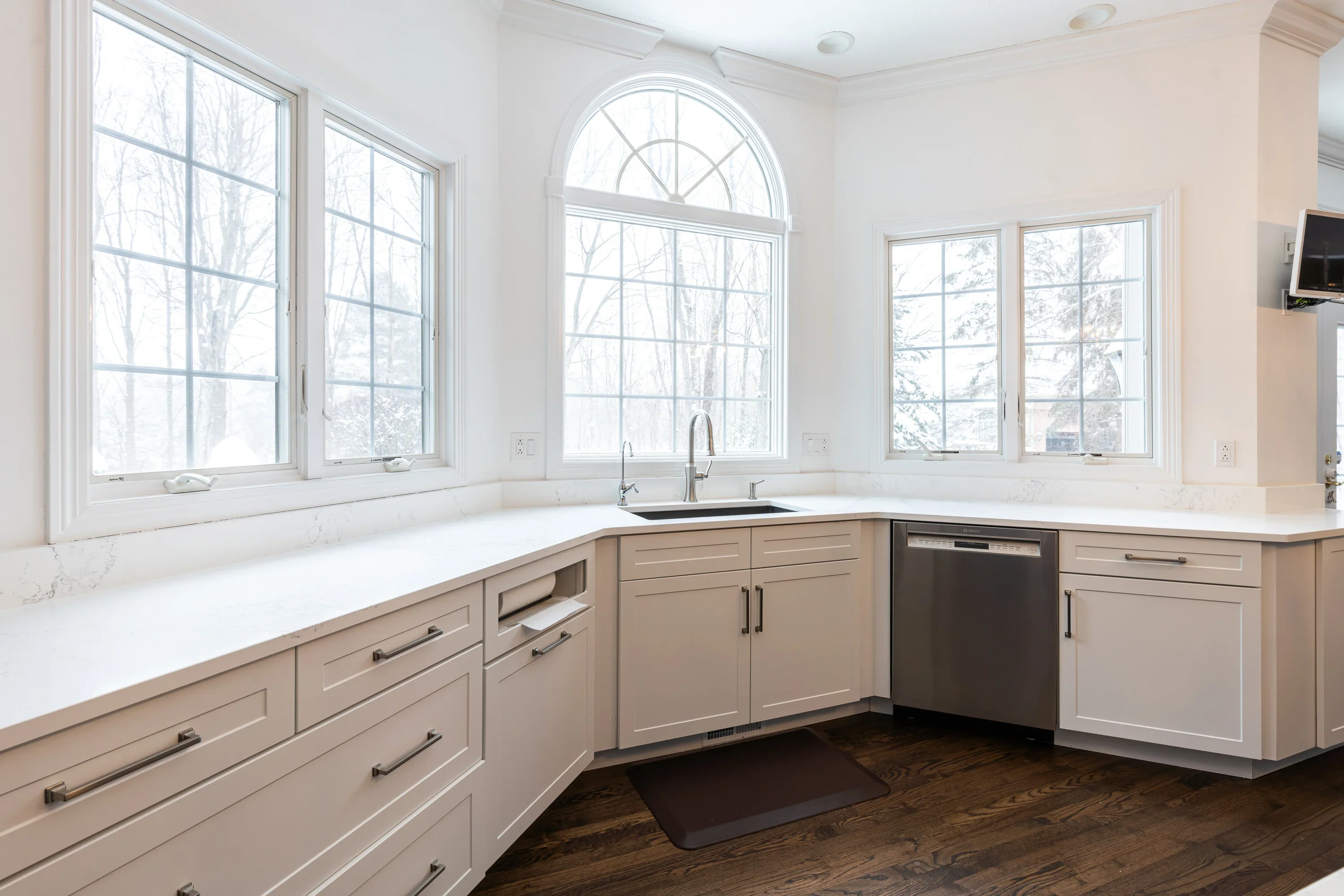 Light wood kitchen cabinets with white quartz counters and multiple windows