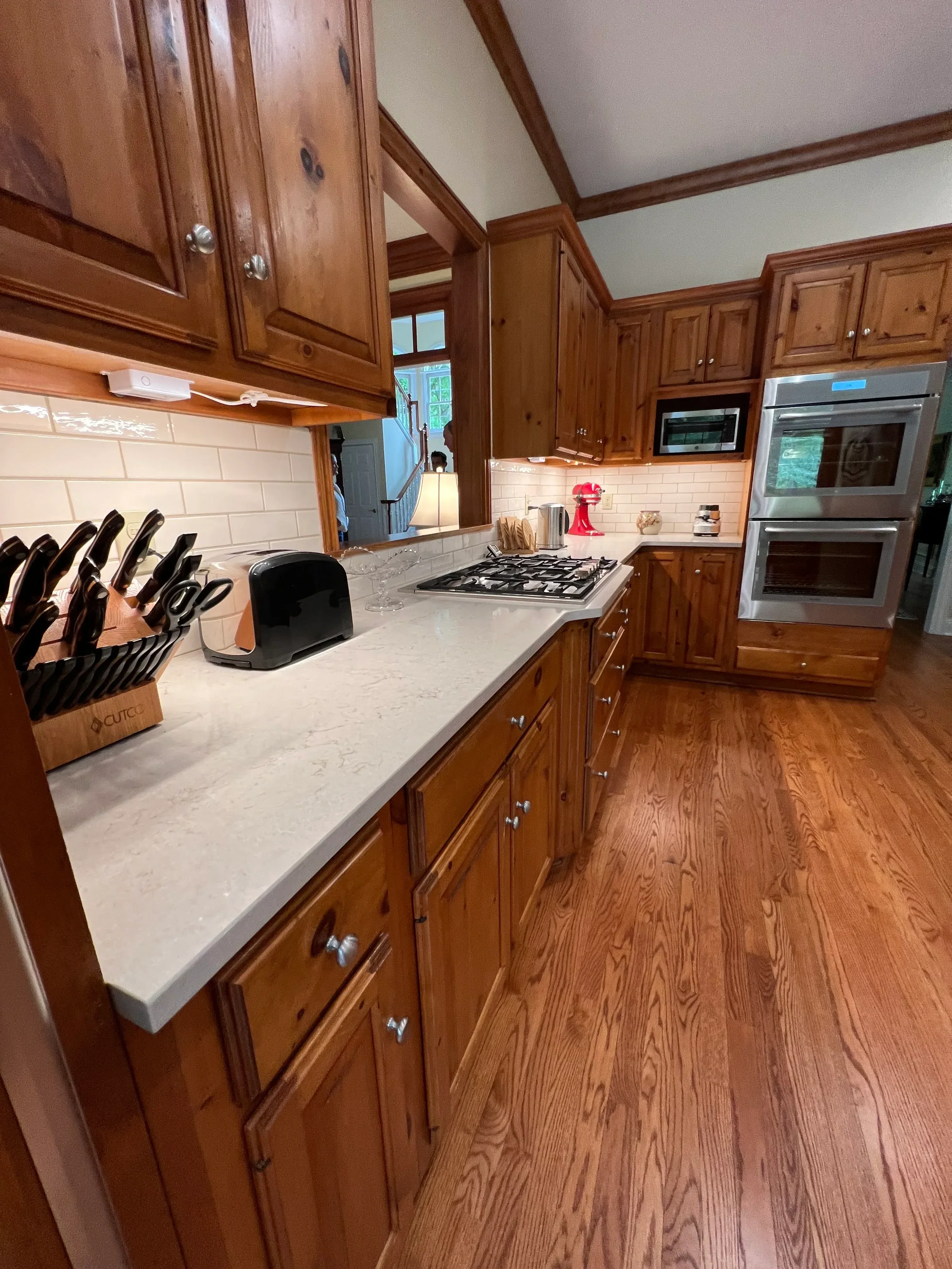 Custom wood kitchen cabinets with chrome hardware, white tile backsplash, and stainless steel appliances
