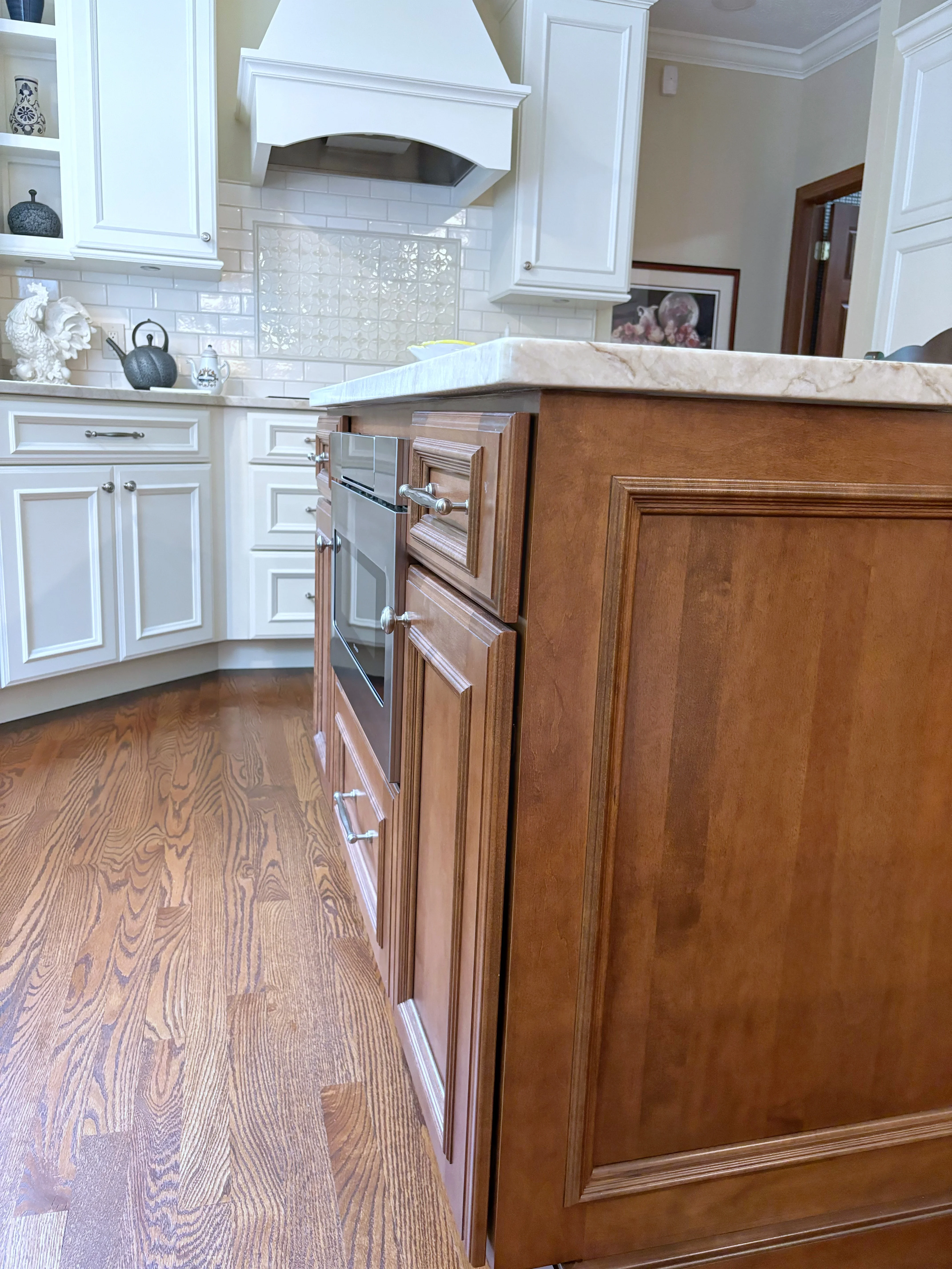 Two-tone kitchen with white and cherry wood cabinetry, marble counters, subway tile backsplash