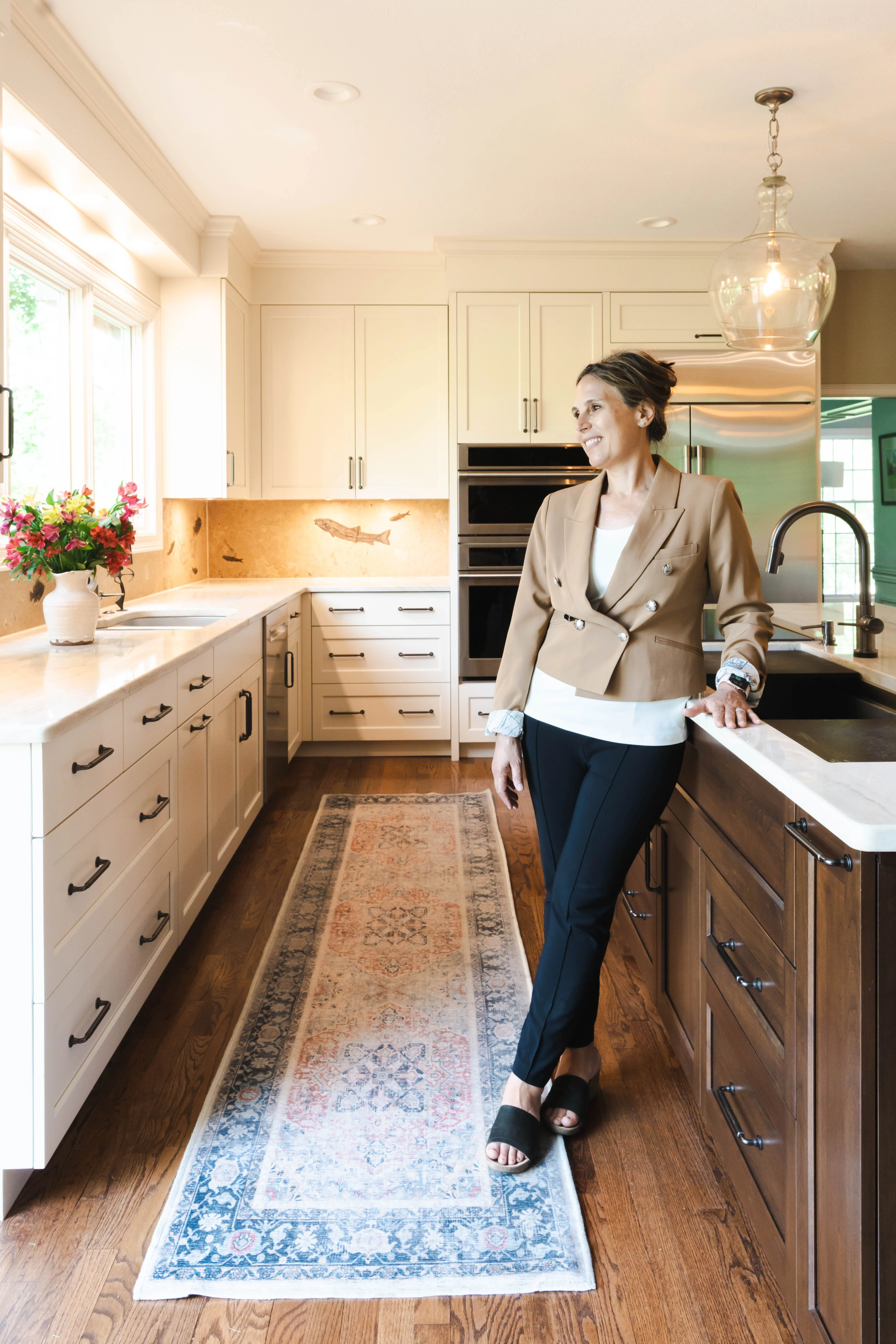 Cream and wood cabinetry kitchen with copper backsplash, quartz counters, and stainless steel appliances