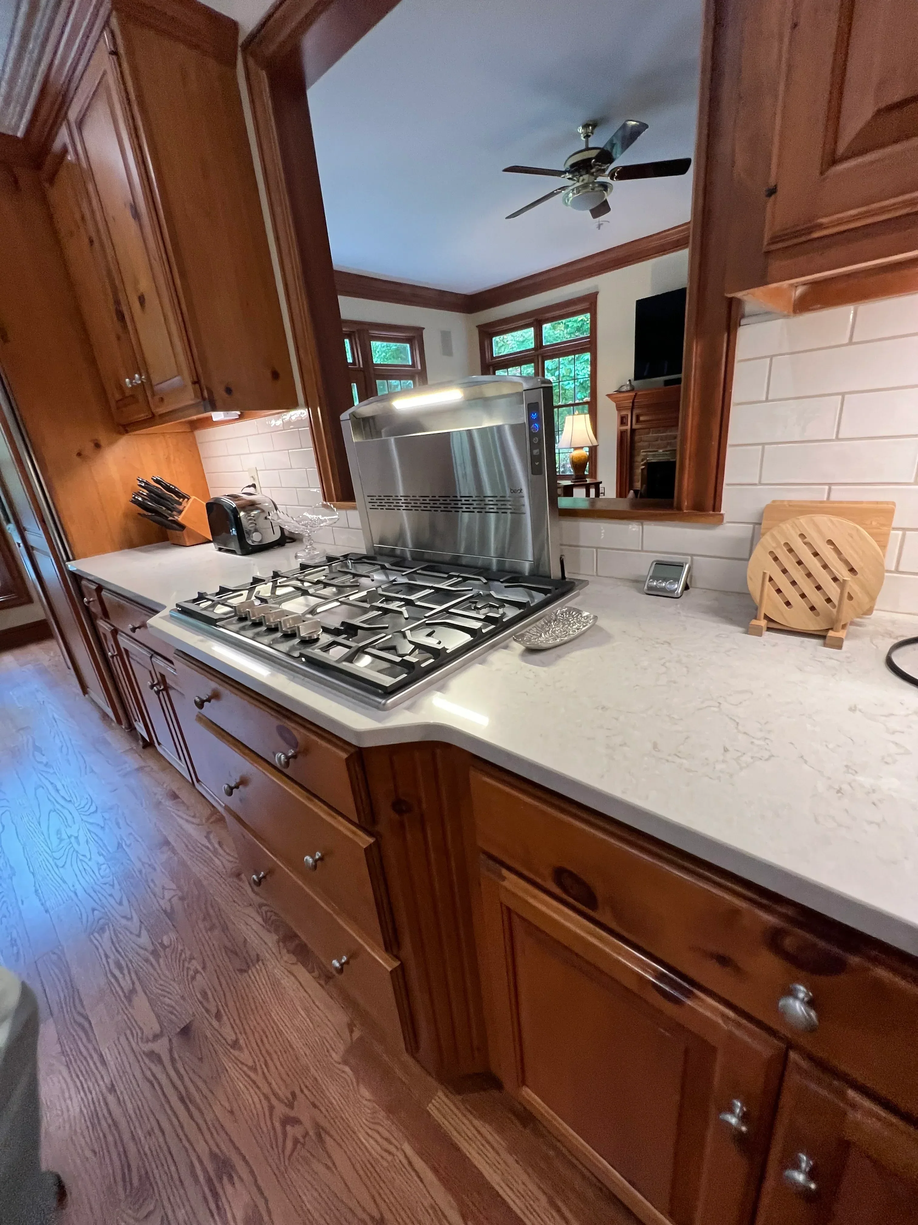 Kitchen with cherry wood cabinetry, white subway tile, stainless steel appliances, and marble countertops