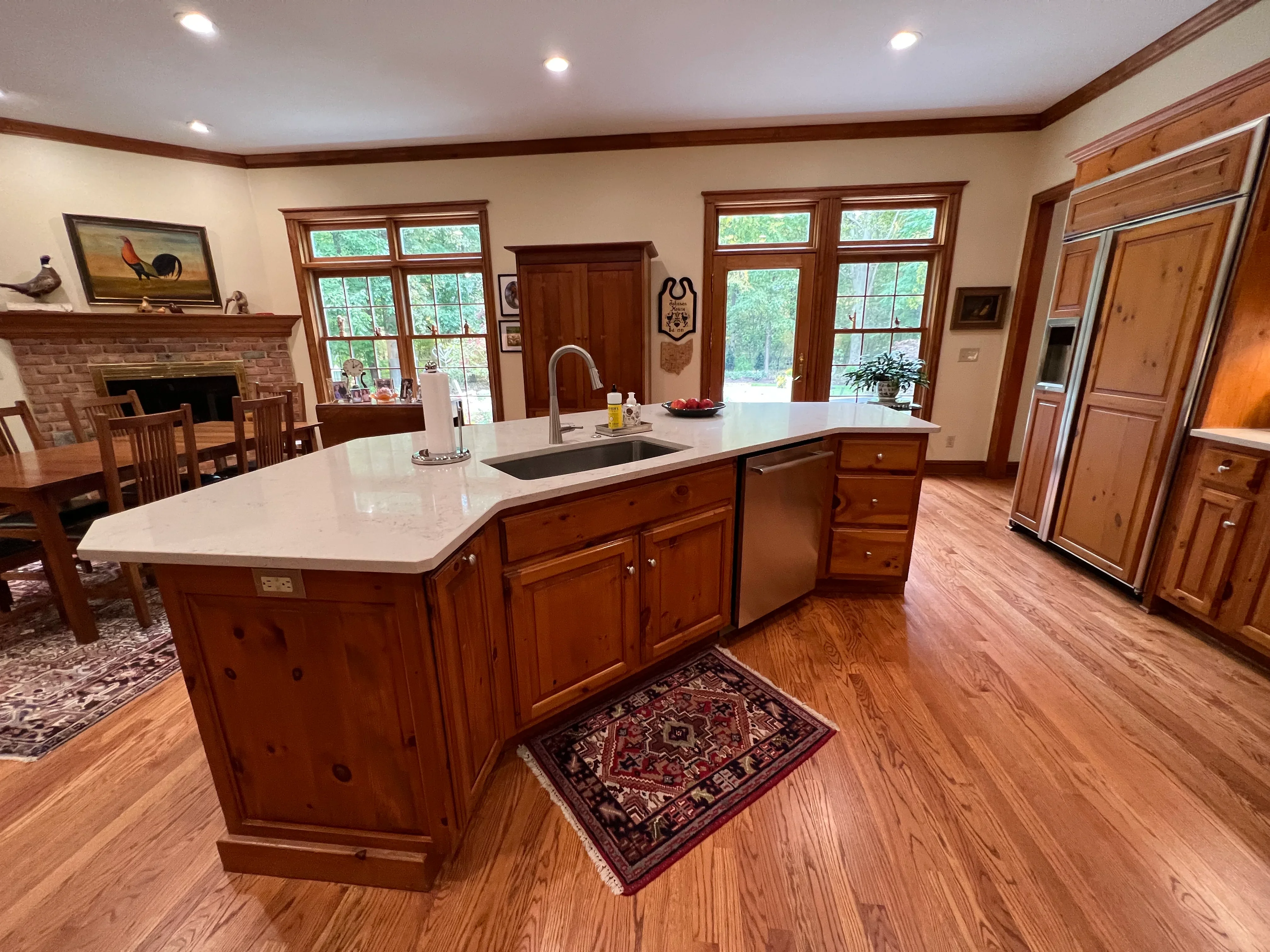 Knotty pine kitchen cabinetry, white quartz island countertop, stainless steel sink and appliances