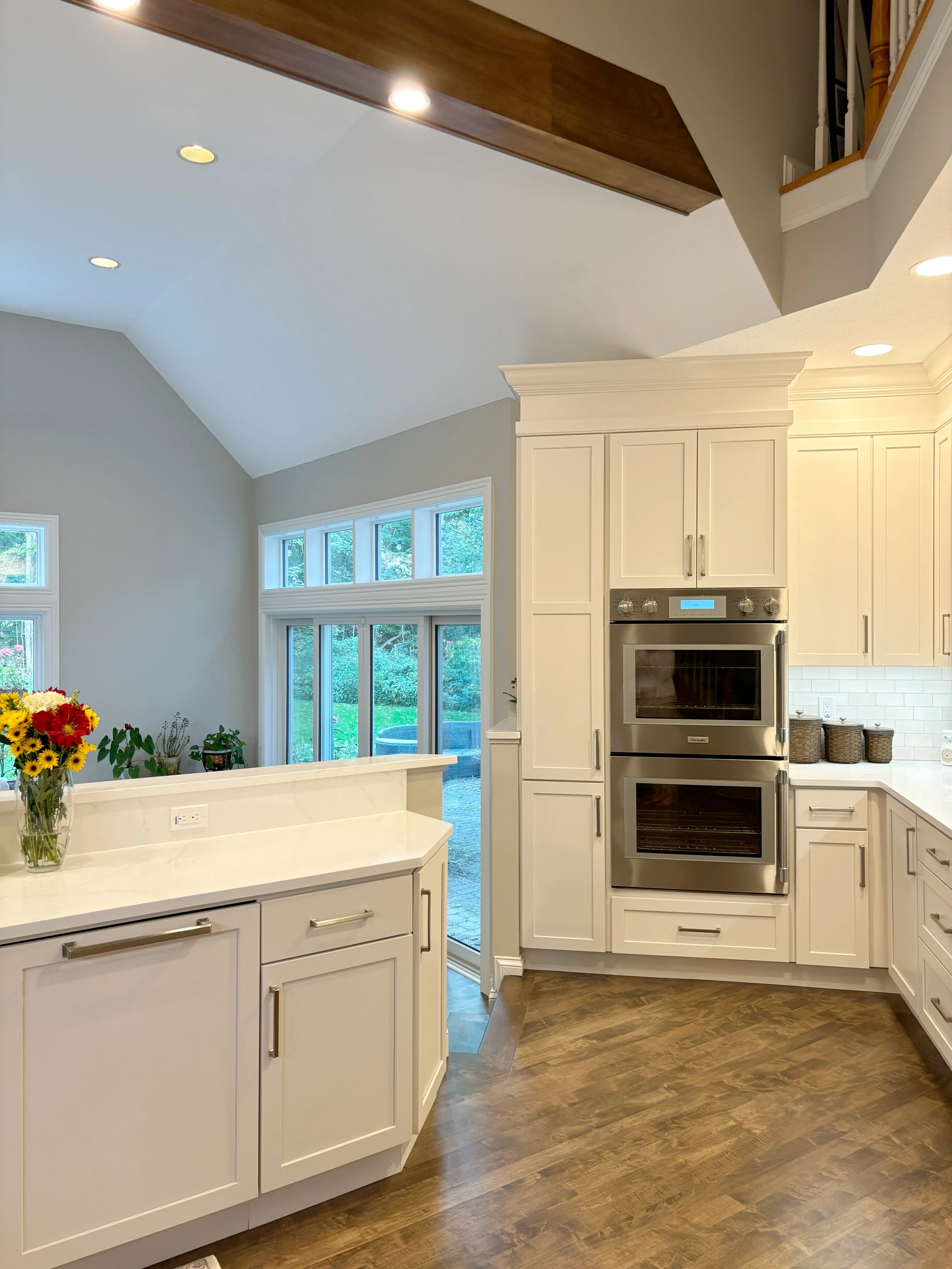 Cream cabinetry kitchen with vaulted ceiling, dual ovens, and herringbone wood flooring
