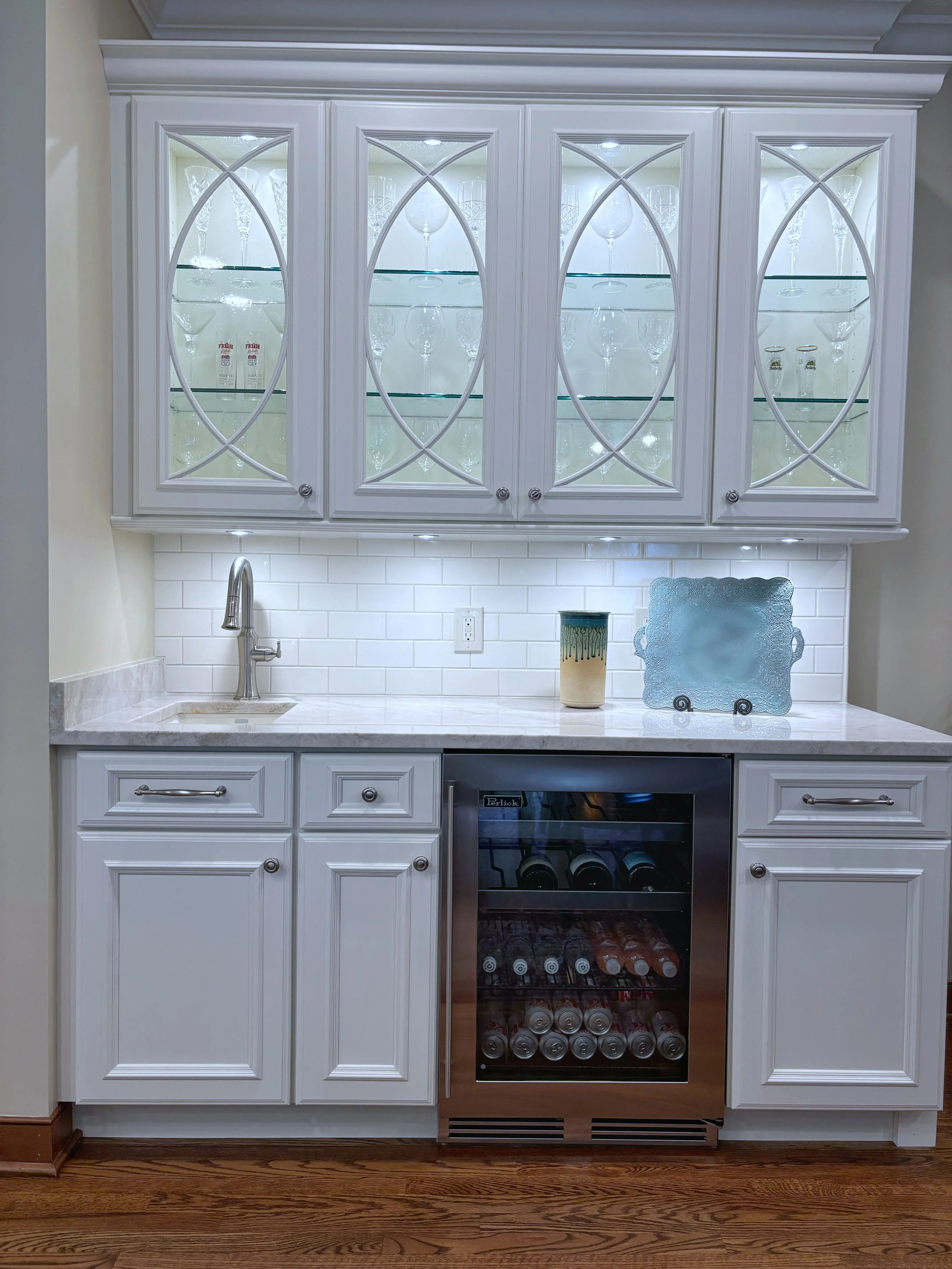 White cabinetry wet bar with glass-front doors, beverage cooler, subway tile backsplash, and quartz countertop