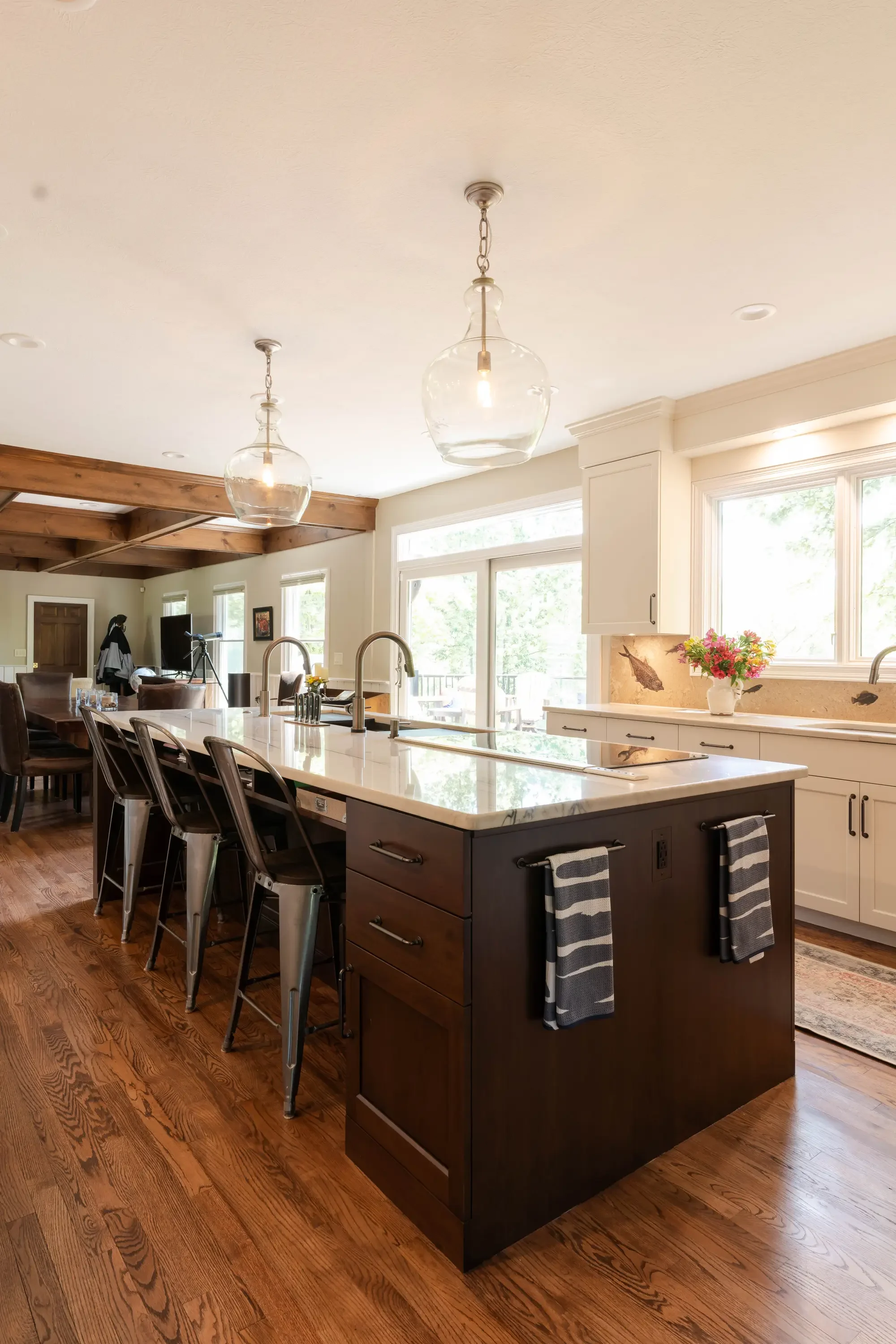 Modern kitchen with cream and dark wood cabinetry, white quartz counters, island seating, and pendant lights