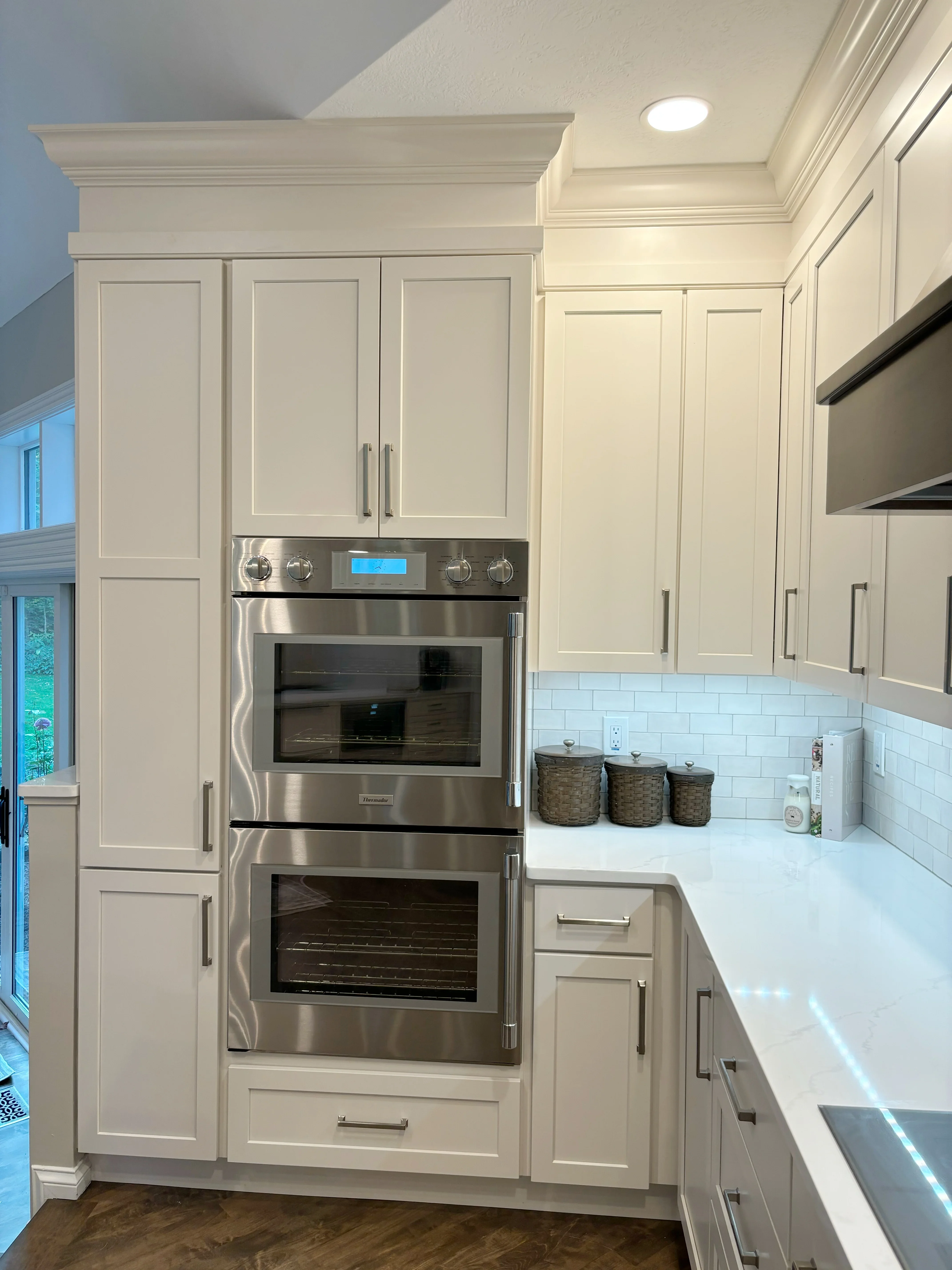 Cream cabinetry with dual stainless steel wall ovens, white subway tile backsplash, and quartz countertops