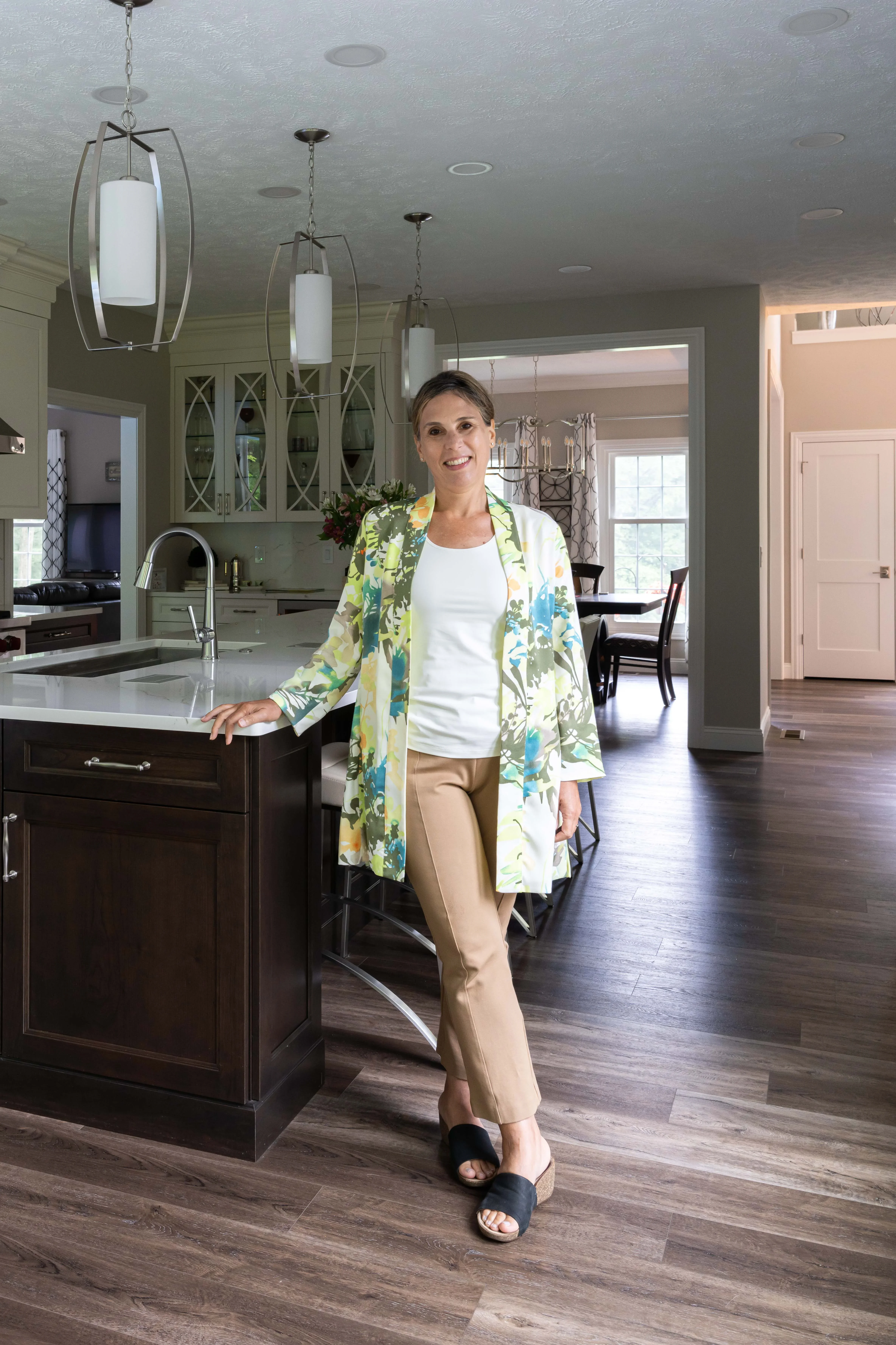 Sage green kitchen cabinetry, dark wood island, white quartz counters, pendant lighting, hardwood floors