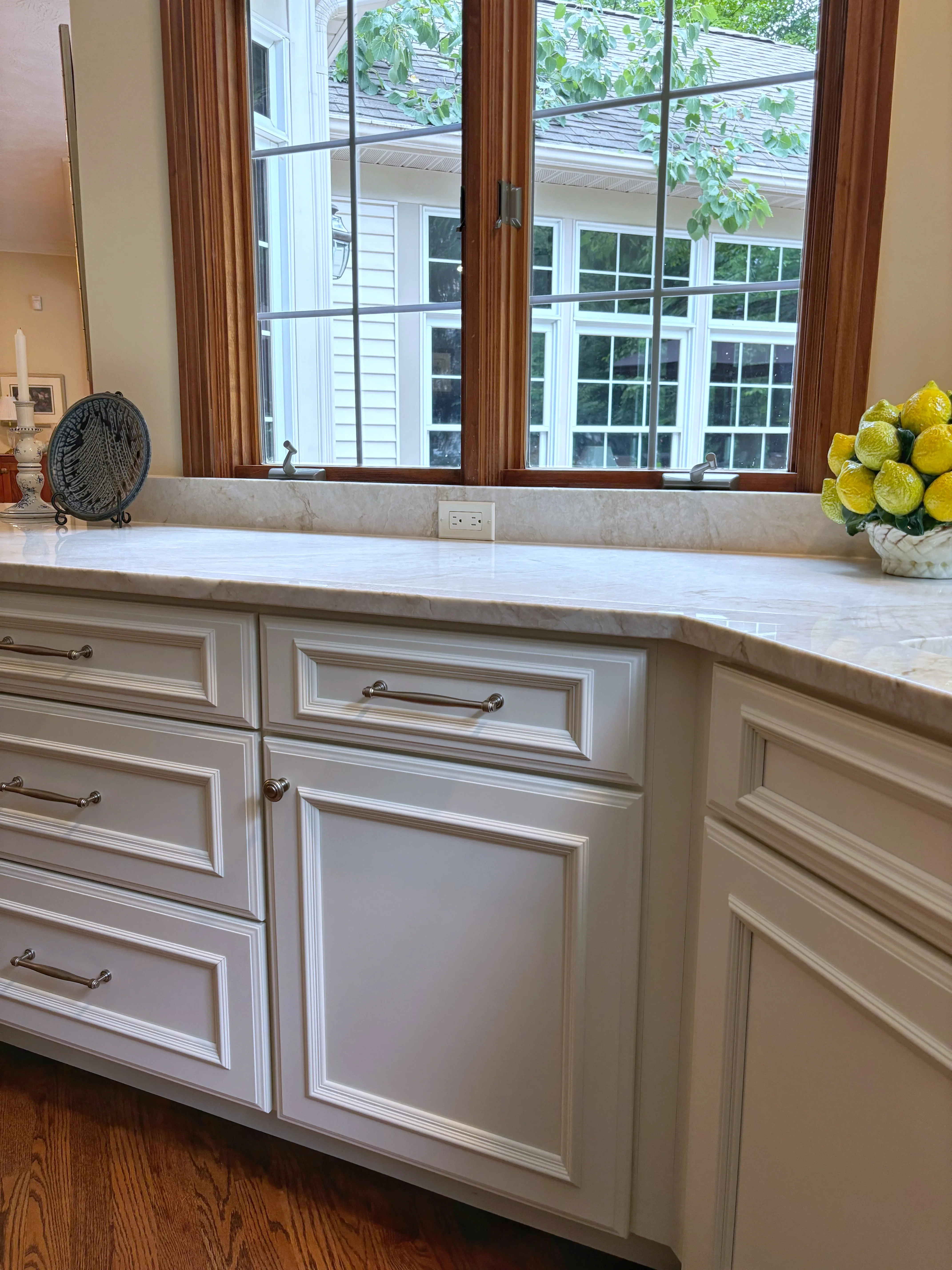 Cream painted kitchen island with marble countertop, raised panel cabinetry, and brushed nickel hardware