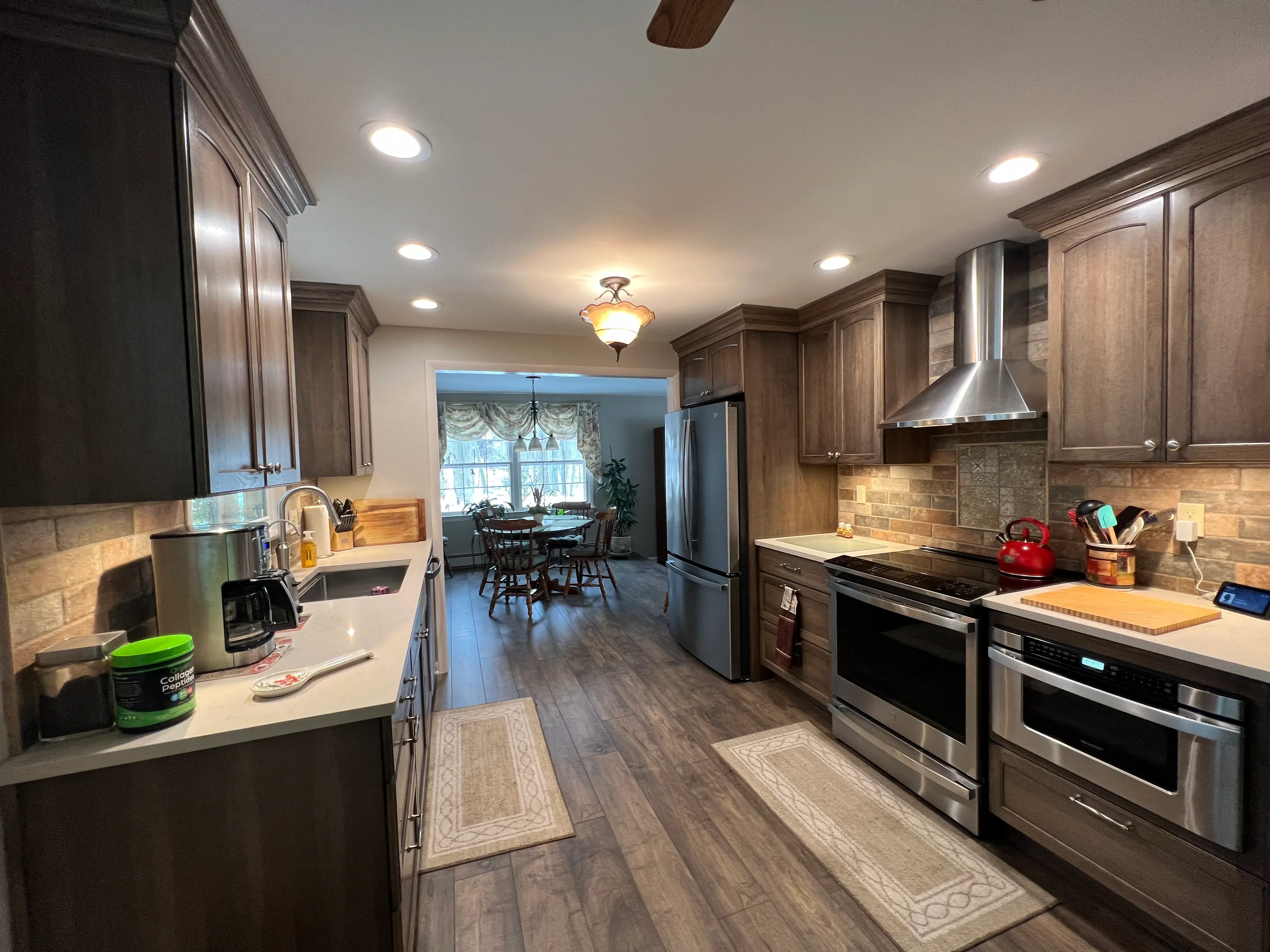 Kitchen with dark wood cabinets, stainless steel appliances, quartz counters, and brick backsplash