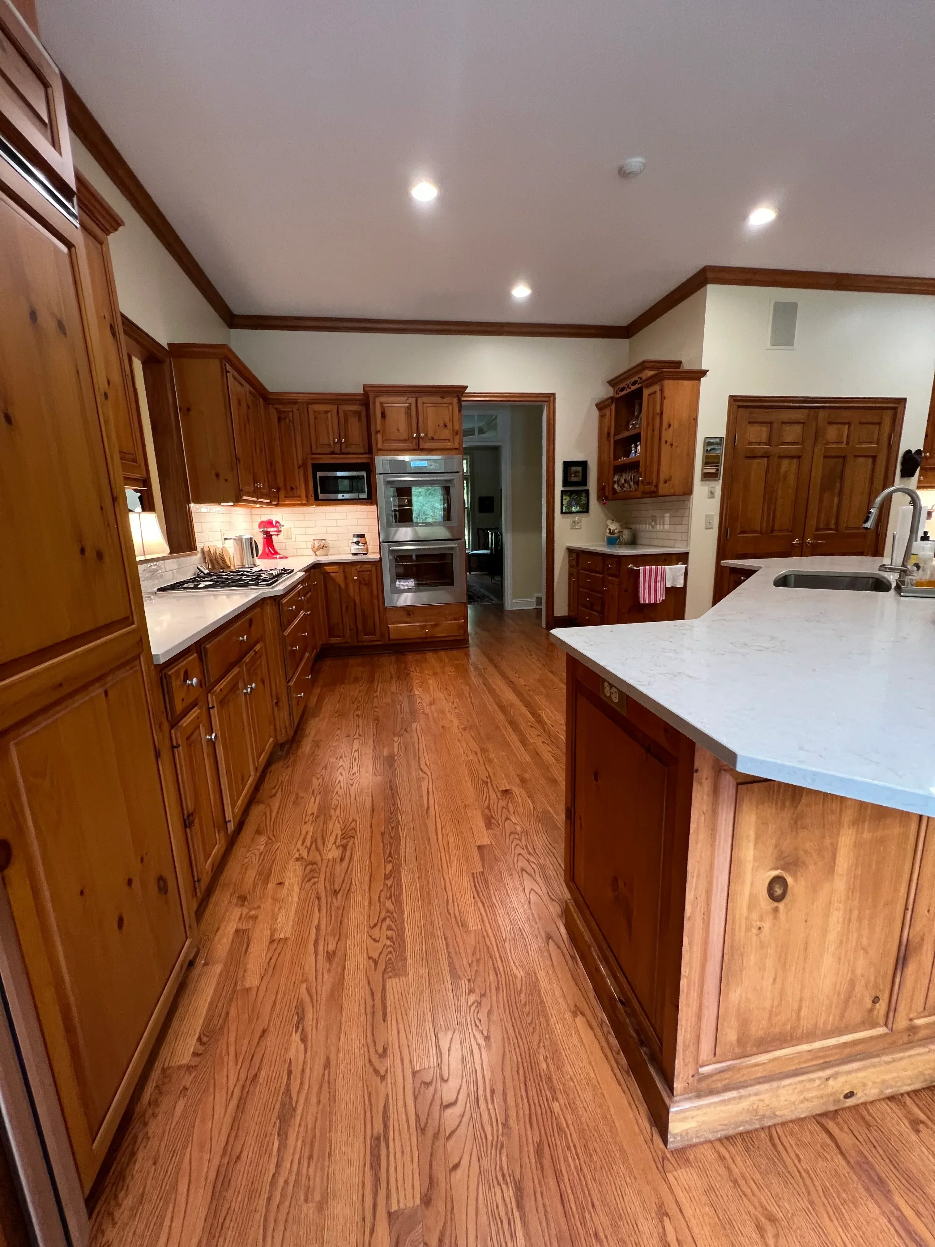 Custom wood kitchen with raised-panel cabinetry, oak flooring, and recessed lighting