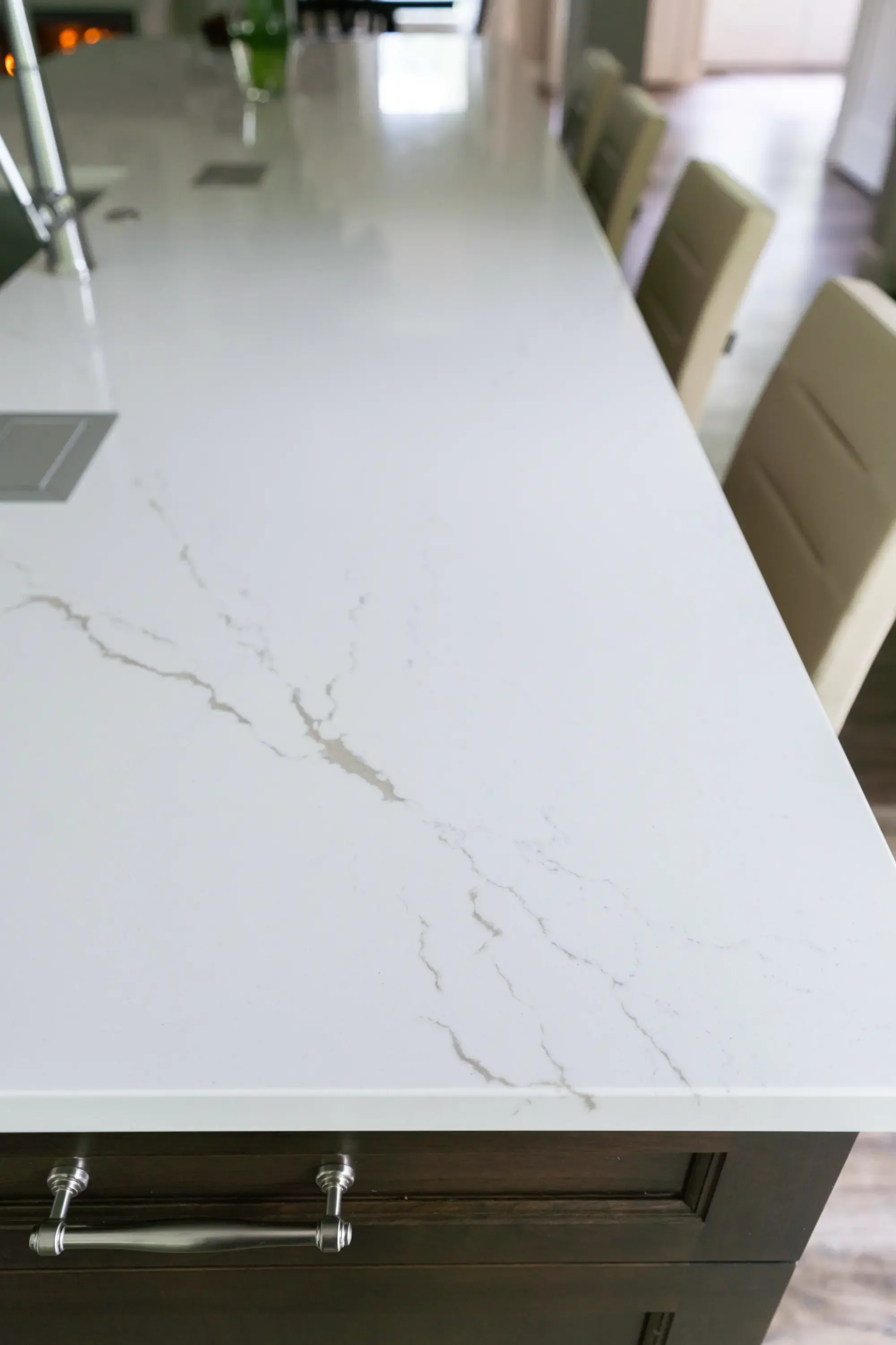 White quartz island countertop with gray veining, dark wood cabinetry, and chrome handles