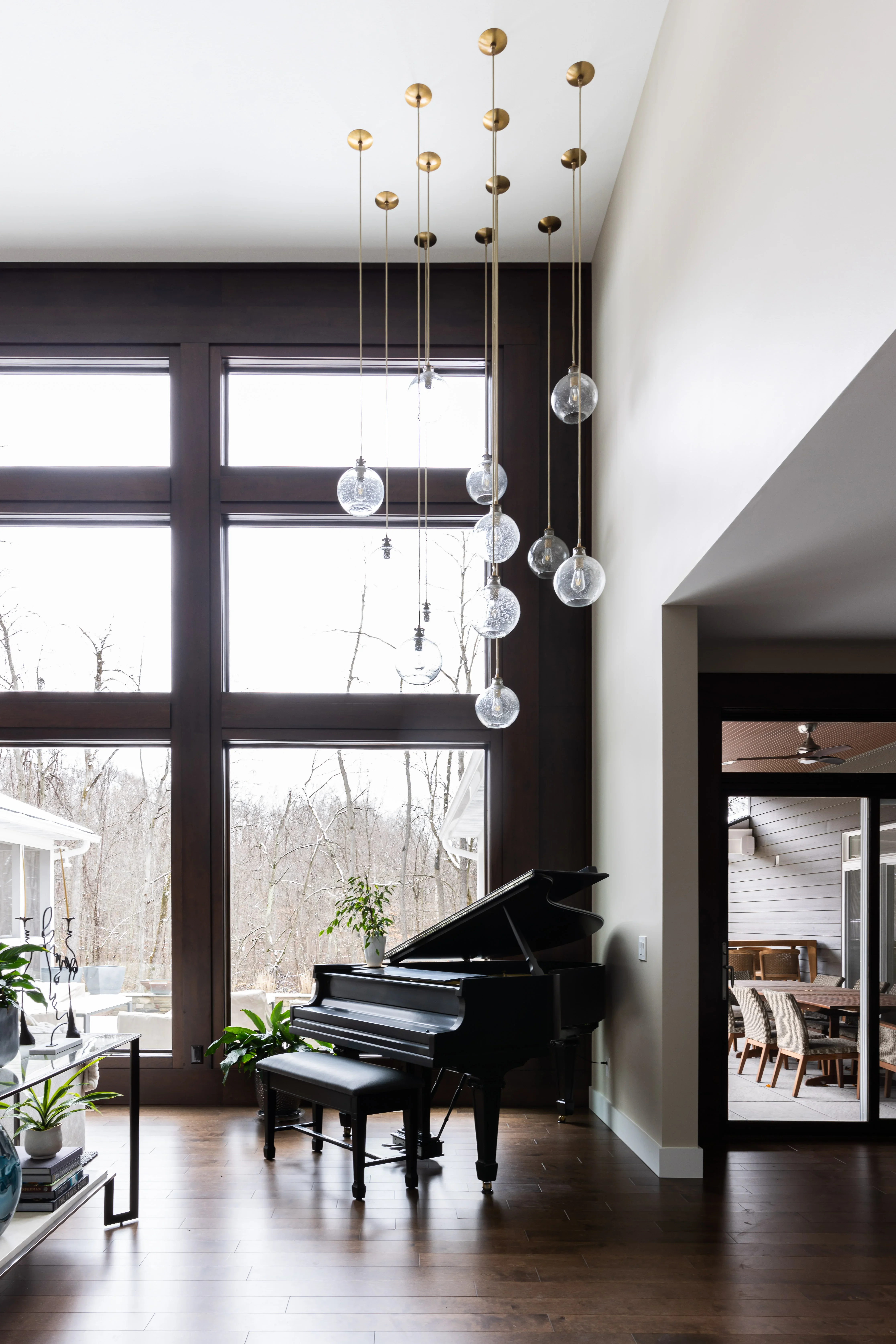 Modern great room with black-framed windows, brass pendant lights, and custom millwork