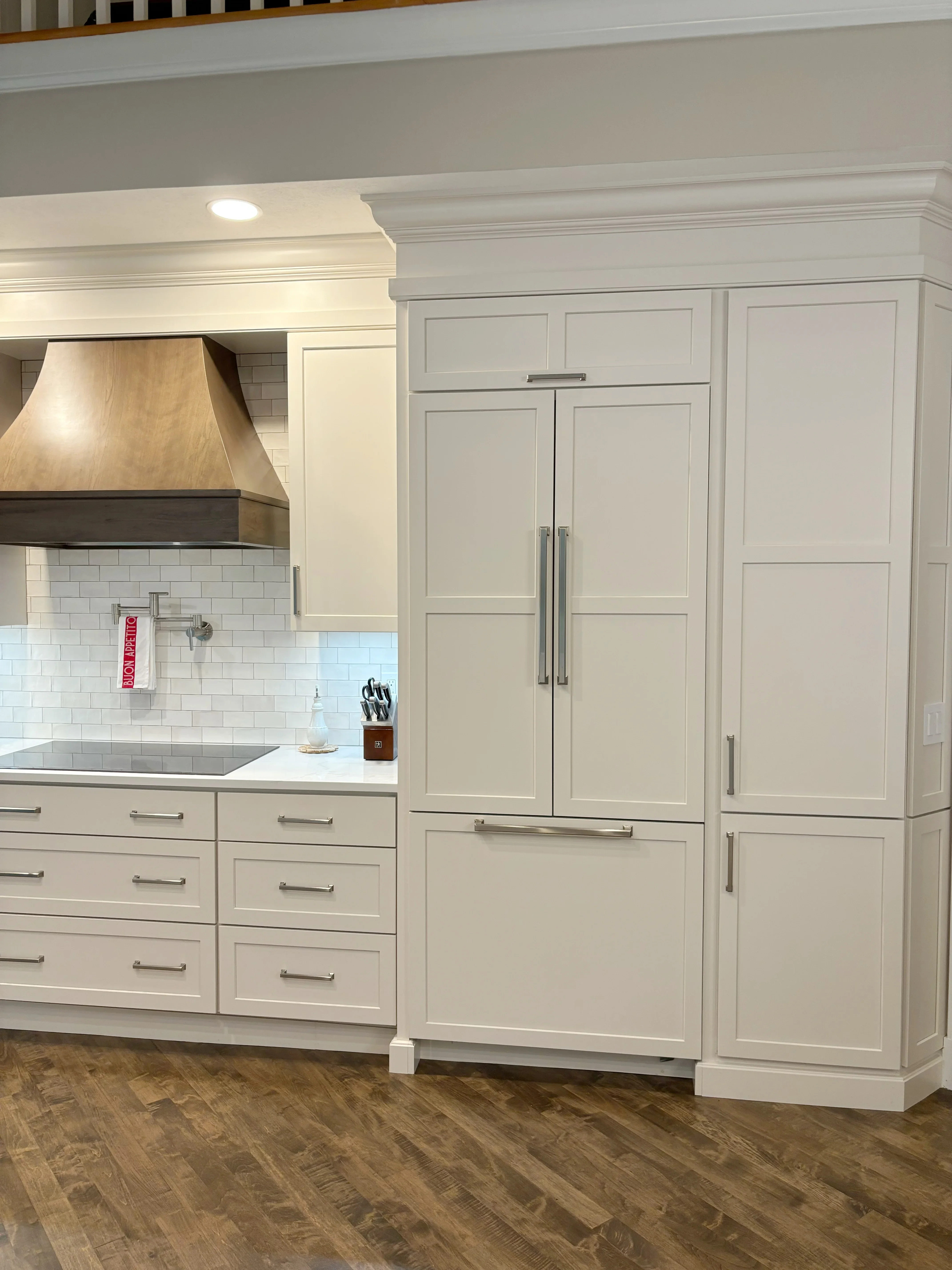Cream cabinetry, subway tile backsplash, wood range hood, stainless steel appliances, recessed lighting