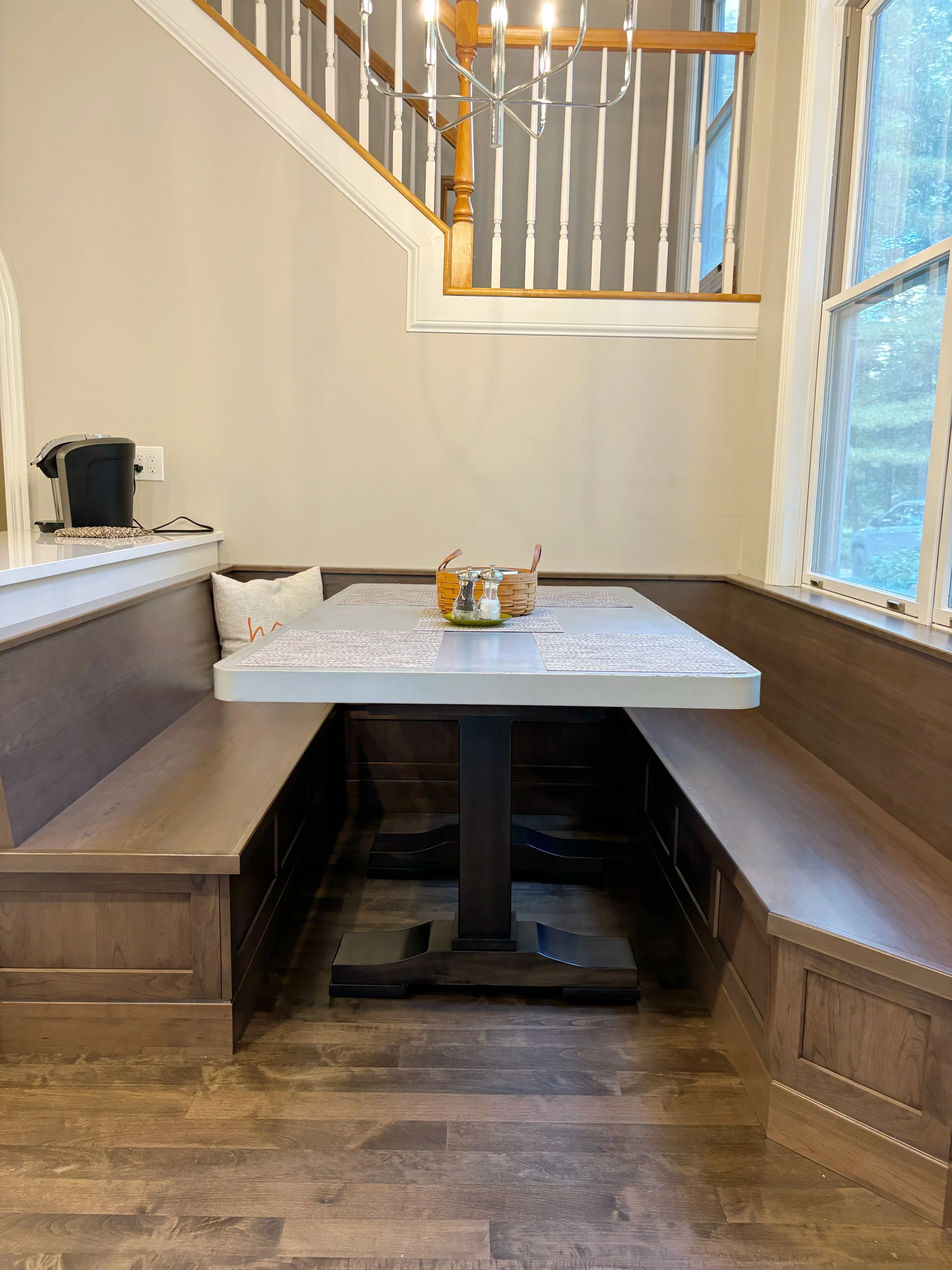 Built-in breakfast nook with wood benches, white quartz table, and hardwood flooring