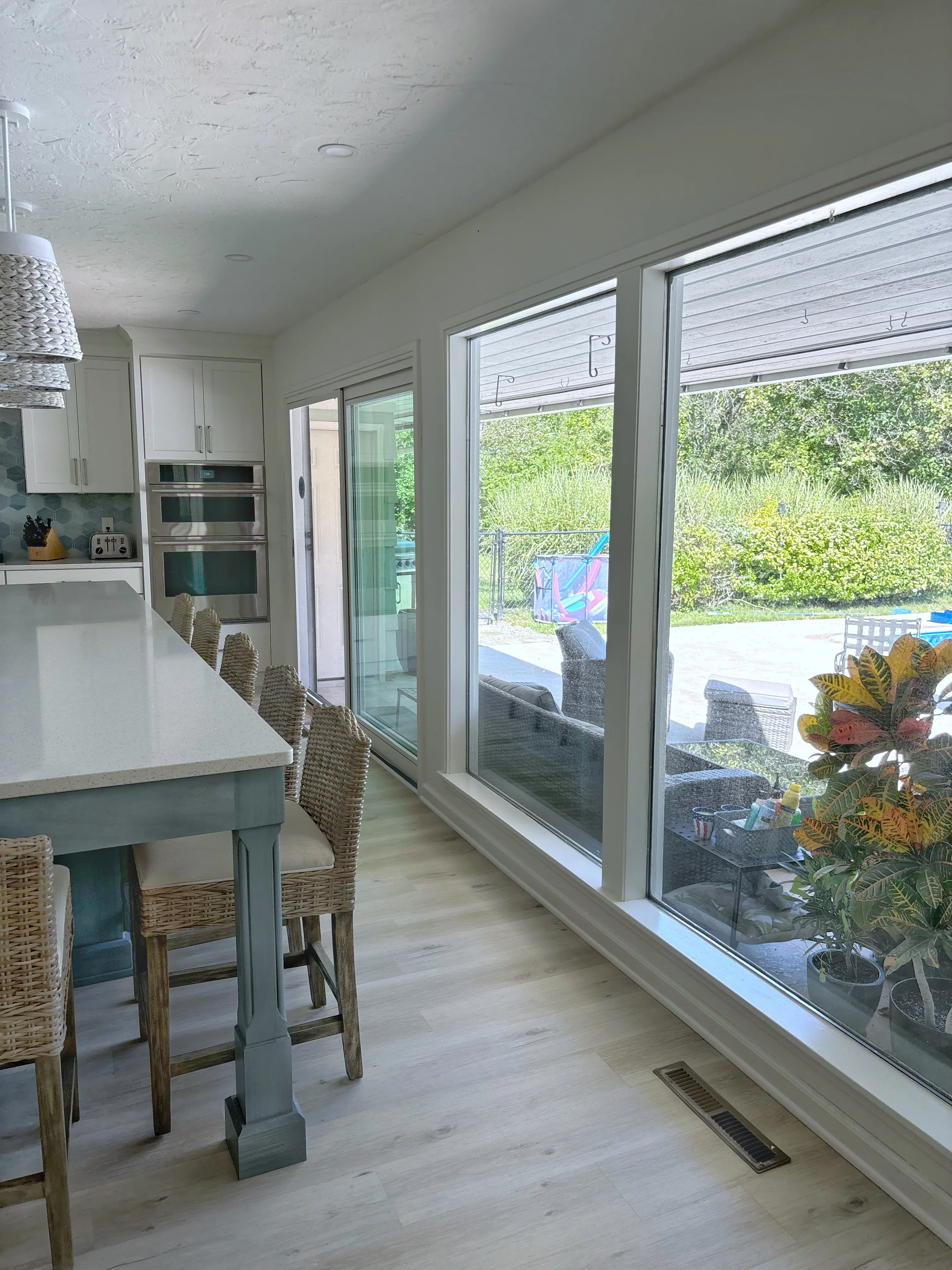 Modern kitchen with white cabinetry, stainless steel appliances, teal island, and sliding glass doors