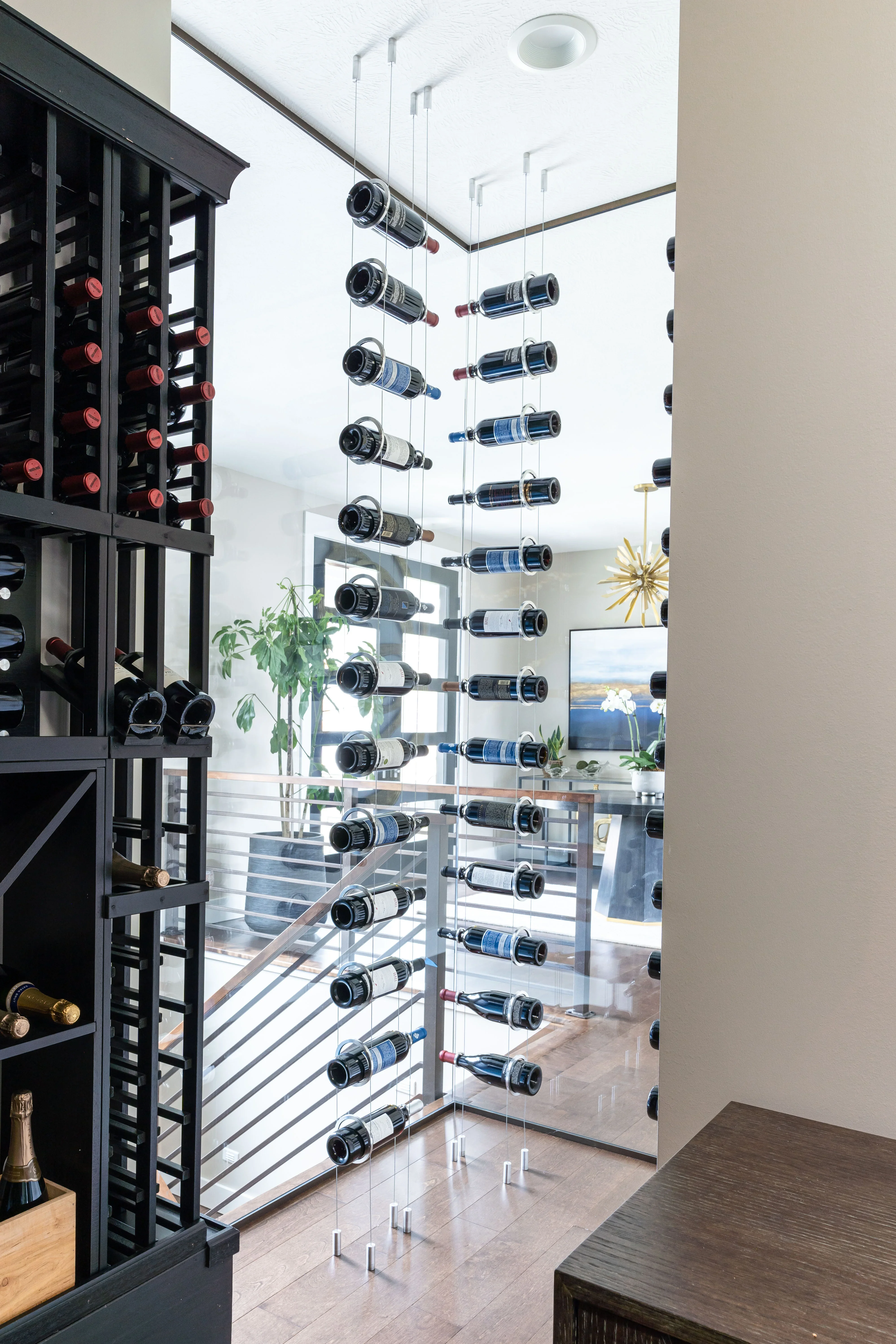 Suspended glass wine shelves with stainless steel cables, black lacquered cabinet, chrome hardware