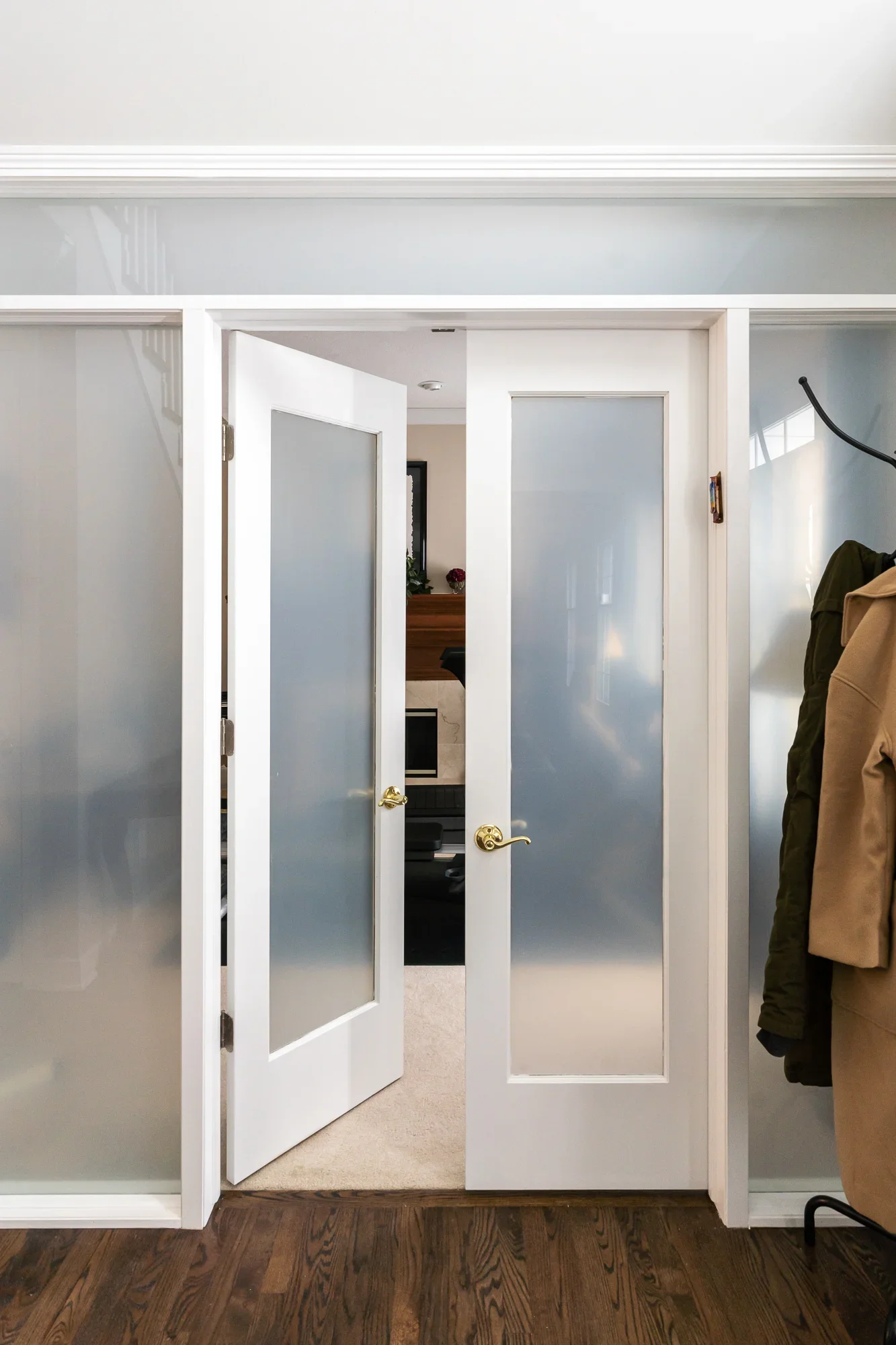 White interior doors with frosted glass panels and brass handles in hallway
