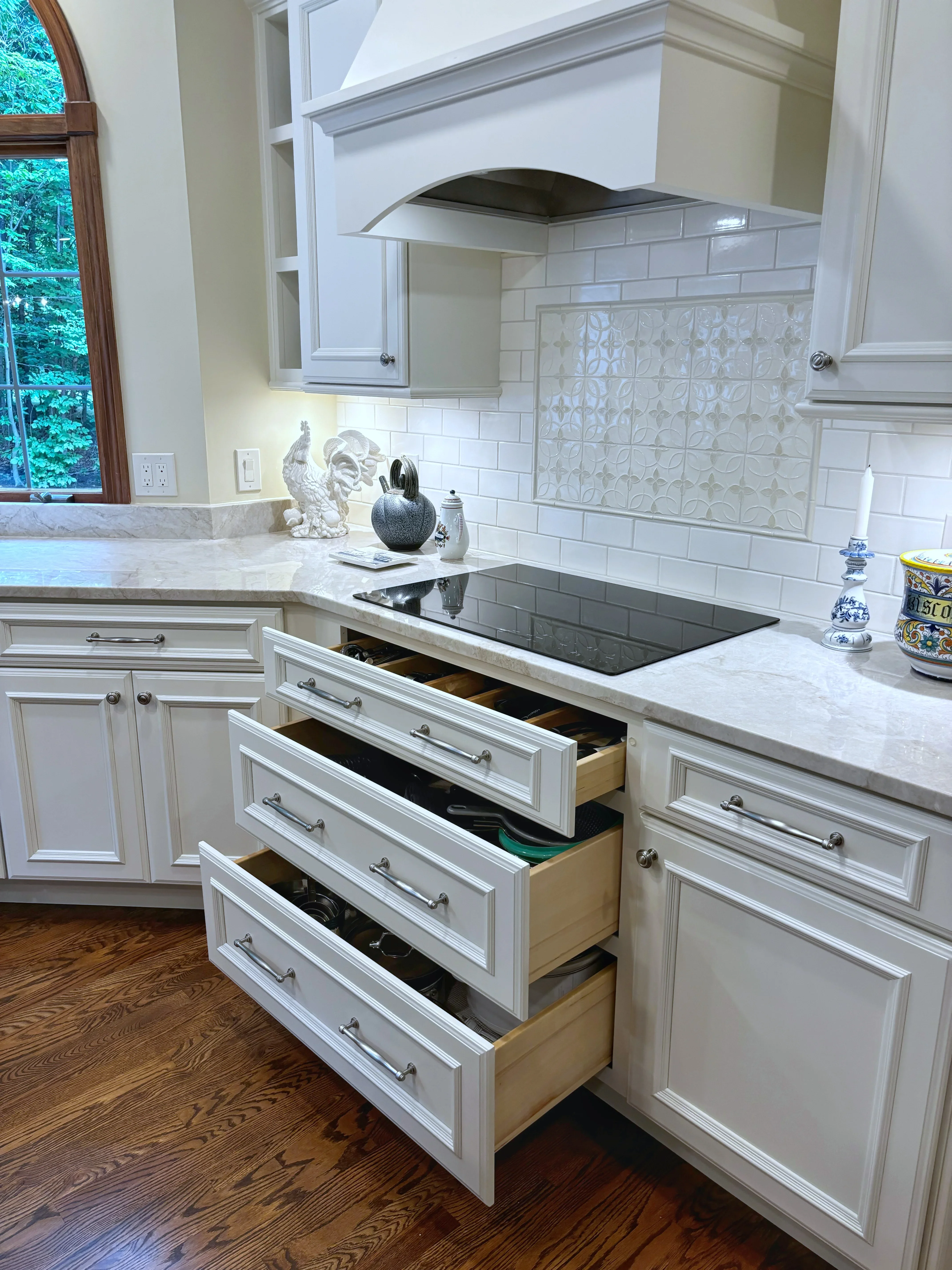 White shaker kitchen cabinets with marble counters, subway tile backsplash, and stainless steel range hood