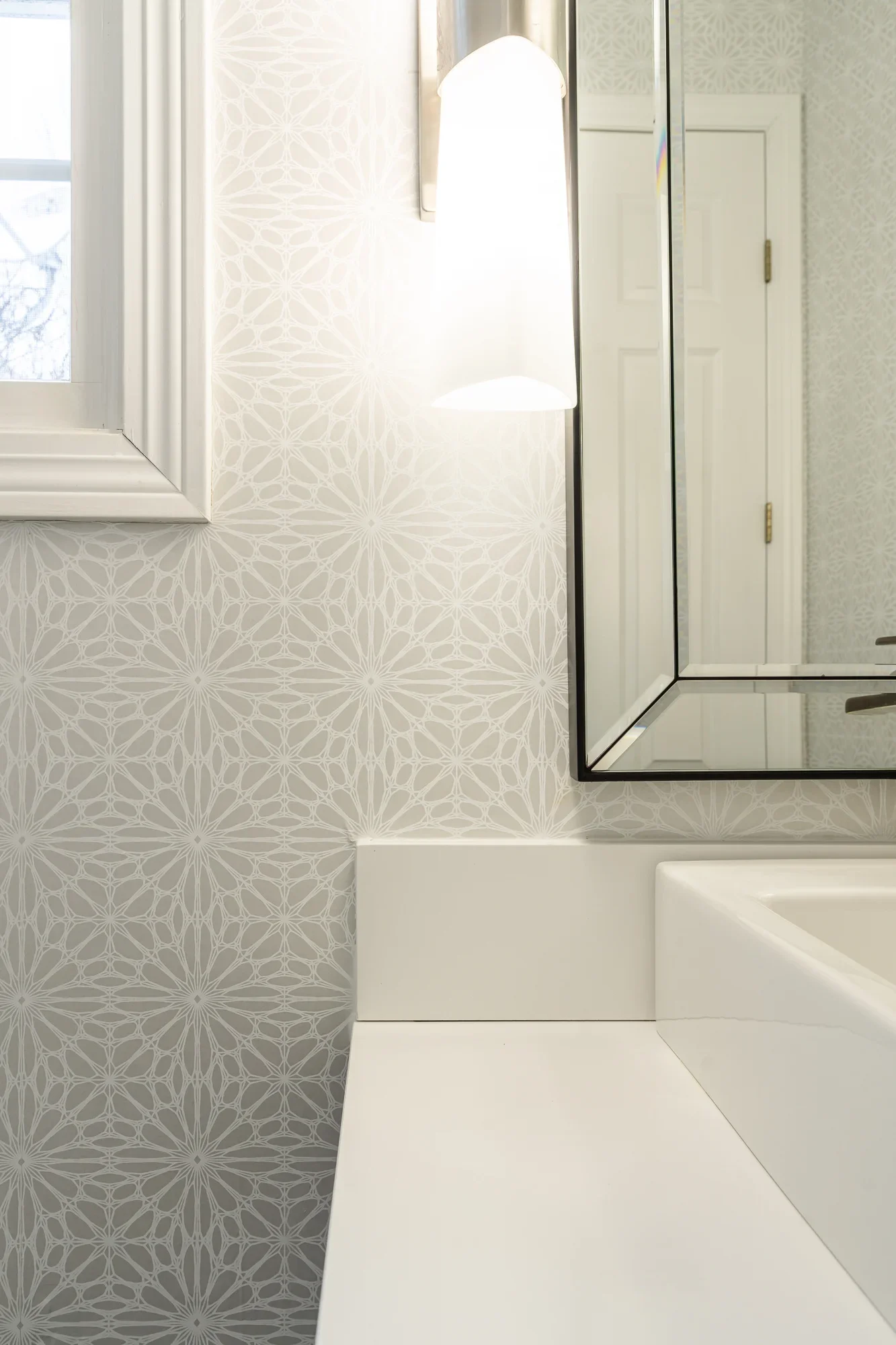 Geometric sunburst tile pattern with white subway tile and framed mirror in bathroom