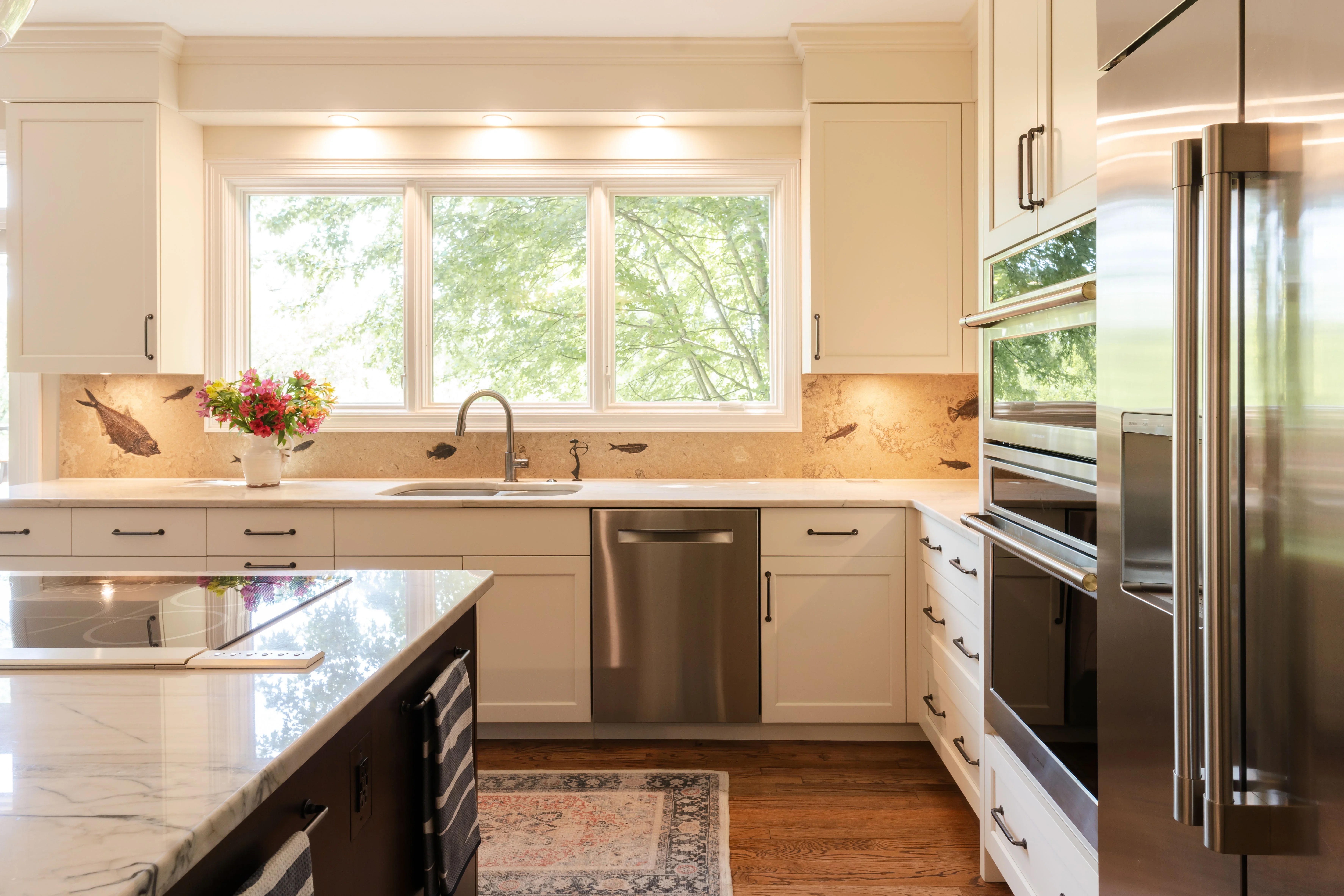 Cream cabinetry, quartz countertops, stainless steel appliances, decorative tile backsplash, hardwood flooring
