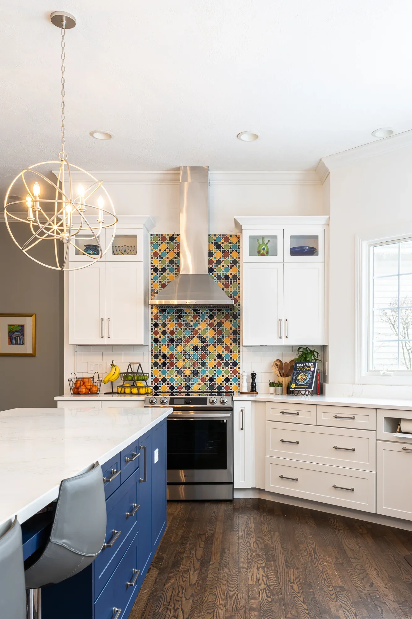 White and navy kitchen with geometric tile backsplash, stainless steel range hood, and quartz countertops