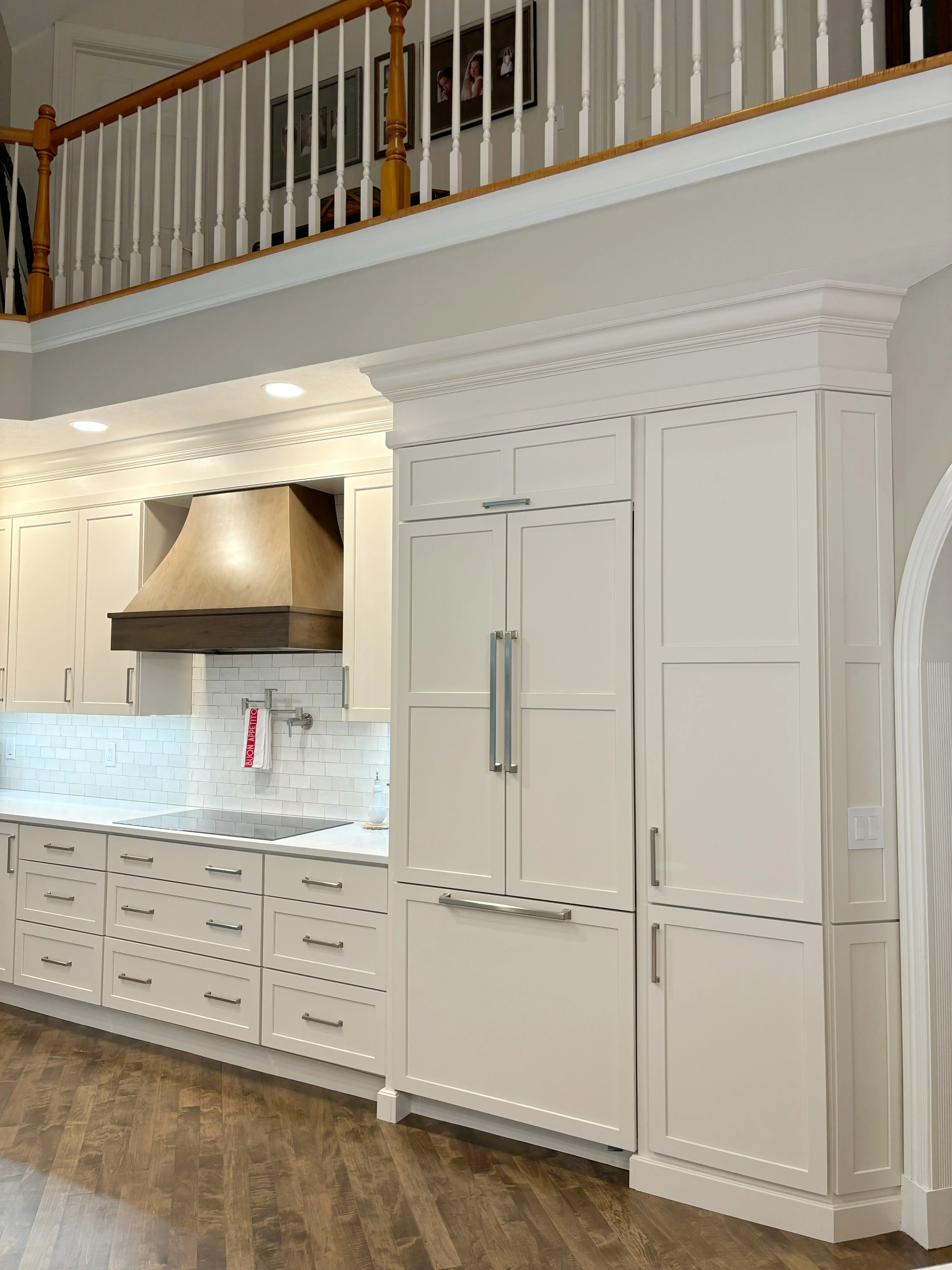 Cream cabinetry kitchen with subway tile, wood range hood, stainless appliances, and island